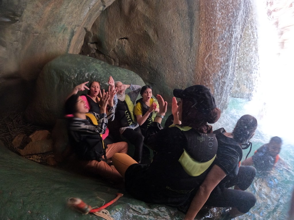 Participants celebrating under the waterfall at Wadi Mujib